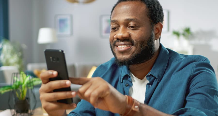 Man sitting down using a home security app on his cell phone
